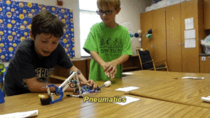 Two friends show off their pneumatics LEGO bricks project.
