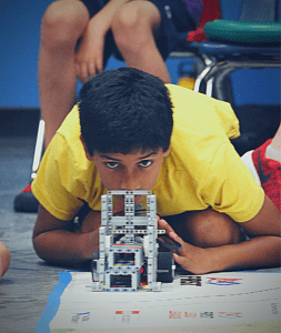 A young robotics engineer carefully places his robot for a run.